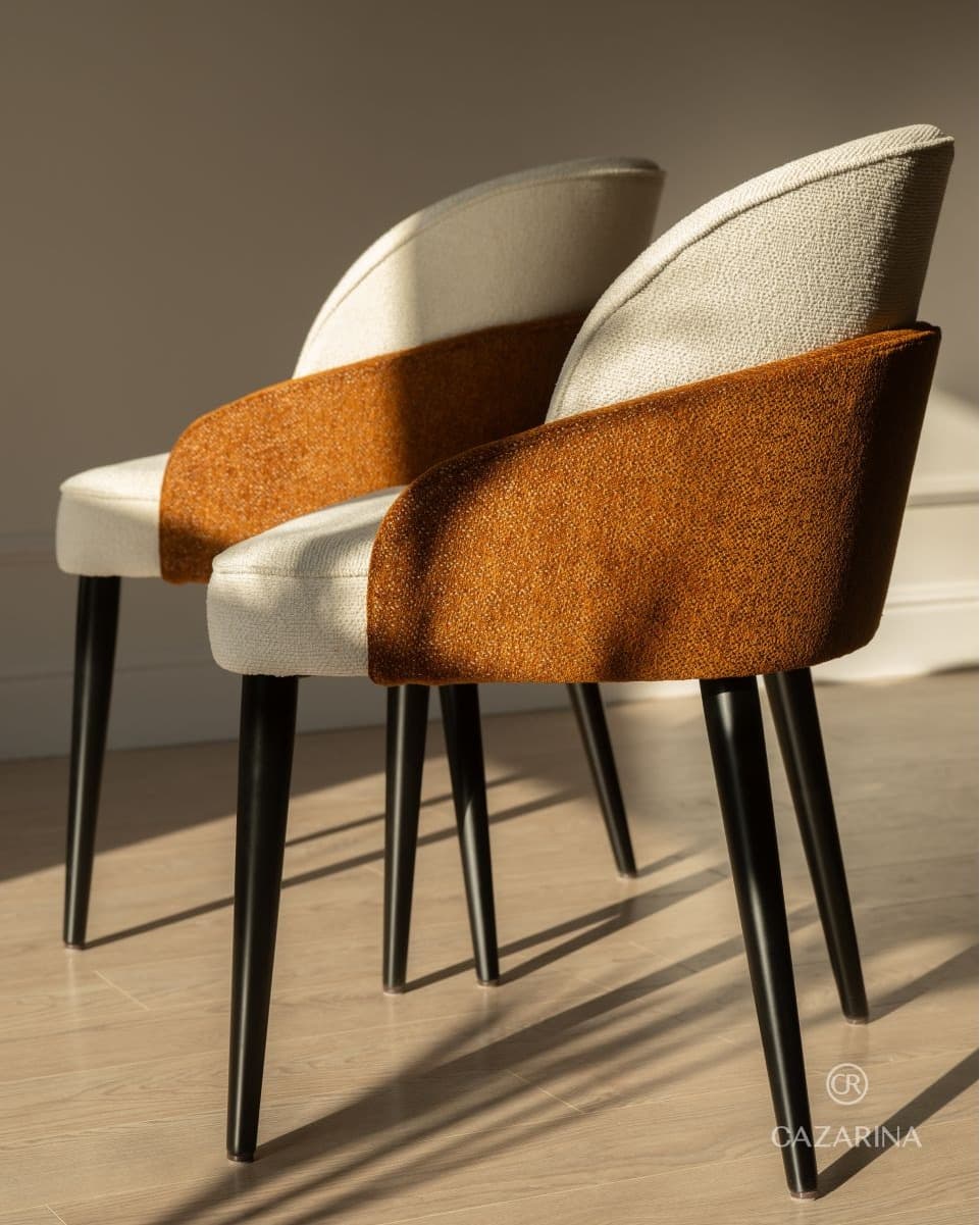 VÉRA dining armchairs with cream and rust-brown textured upholstery and slim black legs in a warm contemporary interior.