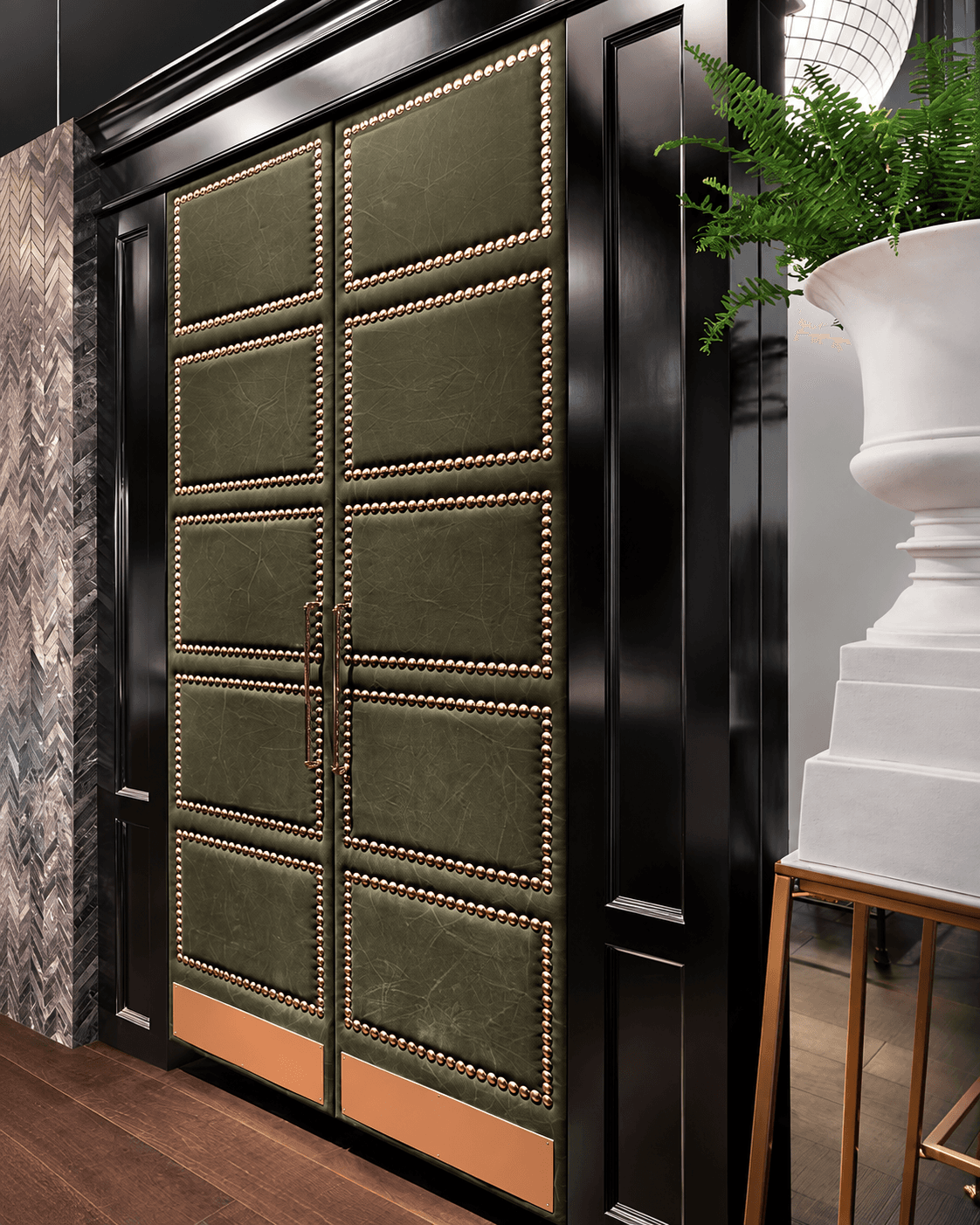 Nailhead Panel Double Main Door in a luxury interior, featuring olive-green upholstered-look panels, metallic nailhead borders, black framing and sculptural vertical handles.