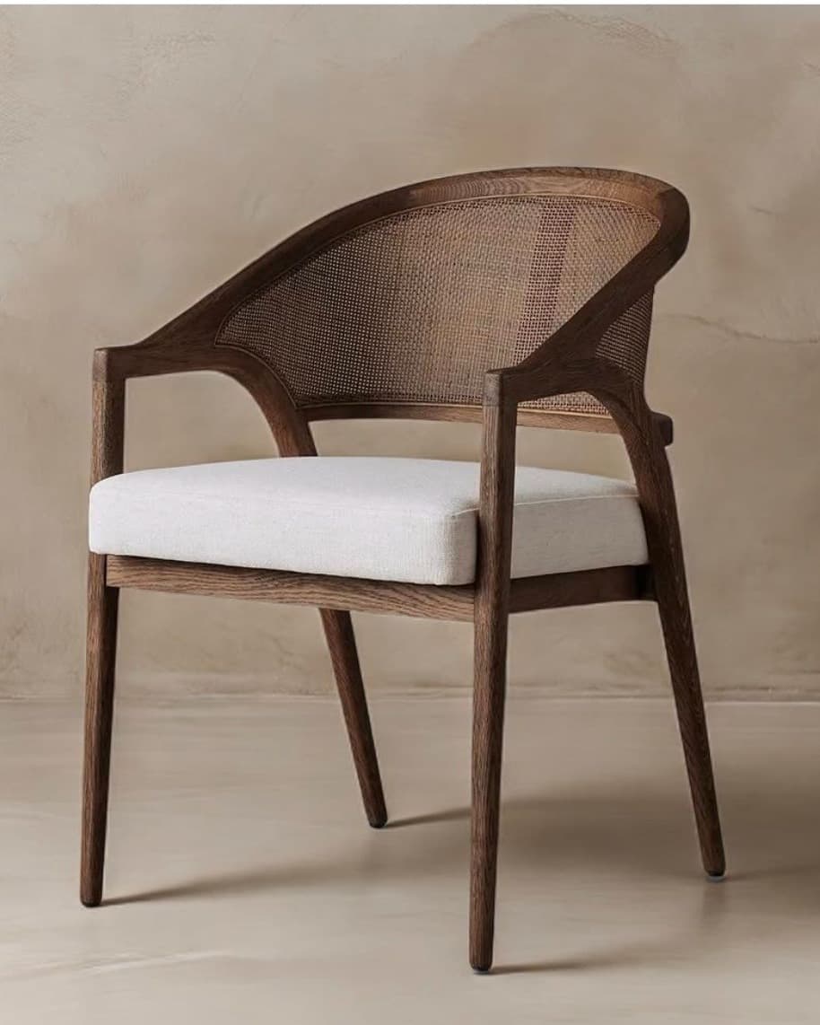 ARCEL premium cane dining armchair with sculptural wooden frame, natural cane backrest and upholstered seat in a neutral interior setting.