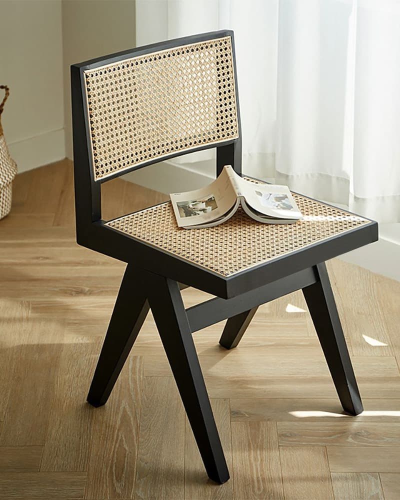 MÉRA modern cane dining chair with black wooden frame and woven cane seat and back in a dining interior.
