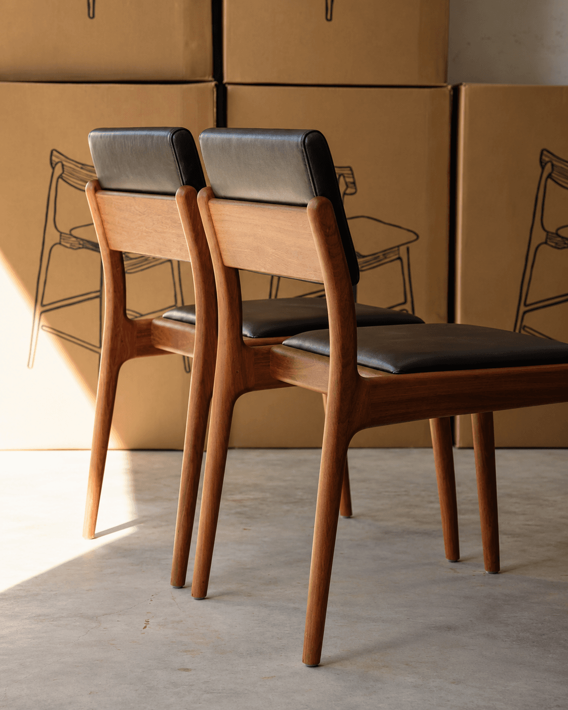 NOA premium wooden dining chair with sculpted wooden back, black upholstered seat and warm walnut frame shown in a dining setting.